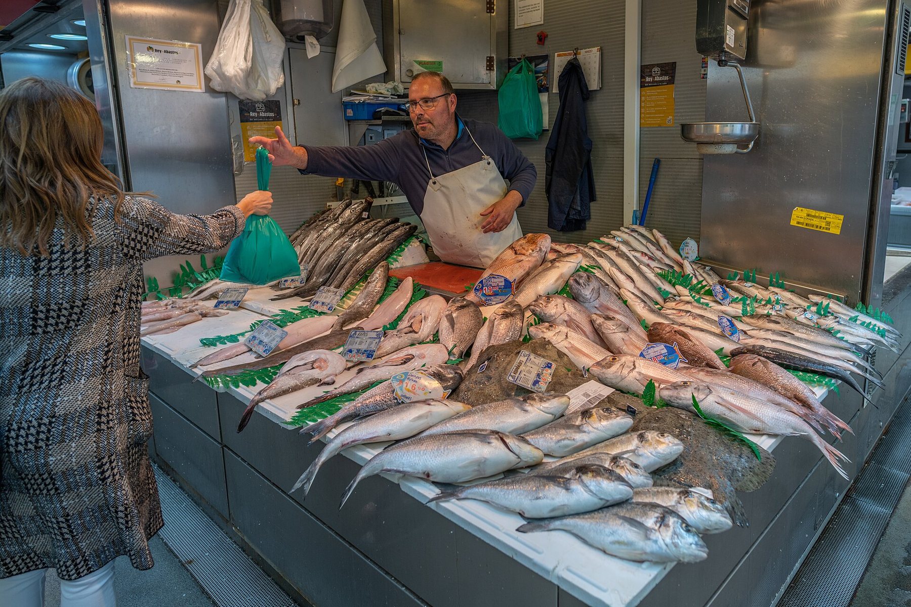 Fiskstånd med färsk fångst och en säljare som betjänar en kund (Atarazanas, Málaga)